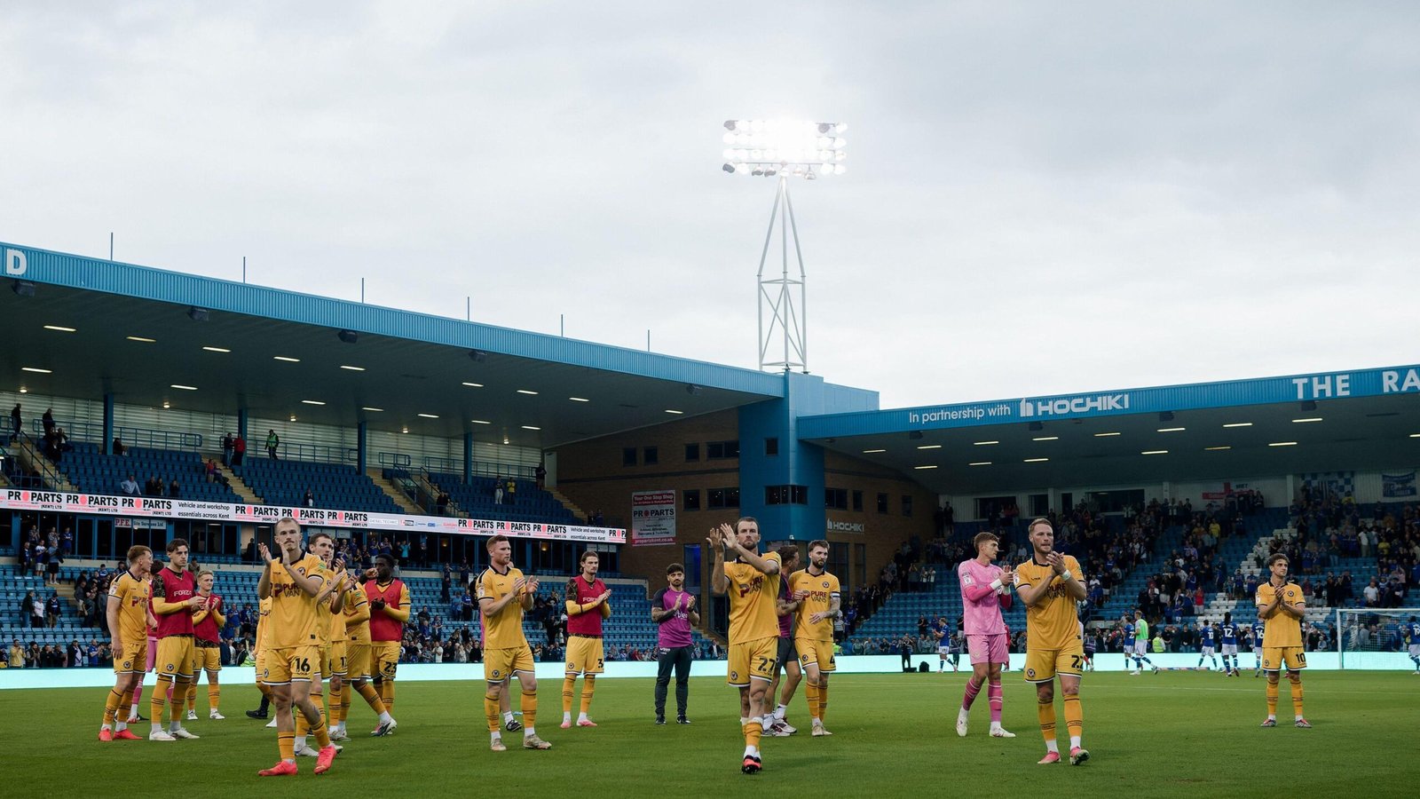 Newport players in all amber applaud travelling fans at Gillingham